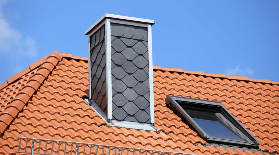 Gashi Dachdeckerei in Bad Oeynhausen, Neu gedecktes Dach mit Kaminverkleidung aus Schieferplatten 